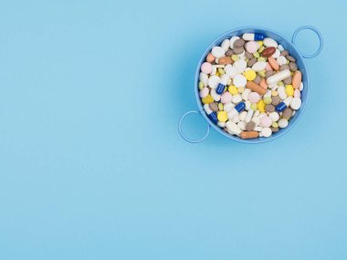 Mavi arka plandaki konteynırda bir sürü hap var. Yukarıdan görünüşü.