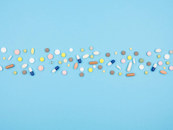 A lot of pills and capsules on a blue background. The view from the top. Medications.