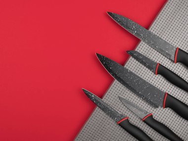 Kırmızı arka planda gümüş bir zemine yerleştirilmiş mutfak bıçağı. Yukarıdan görünüşü.