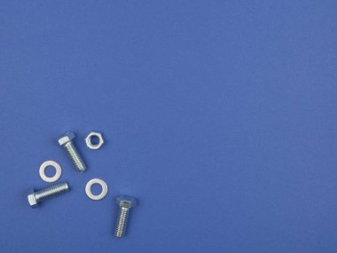 Mavi arka plana bağlanmak için cıvatalar, fındıklar ve diskler. Yukarıdan görünüşü.