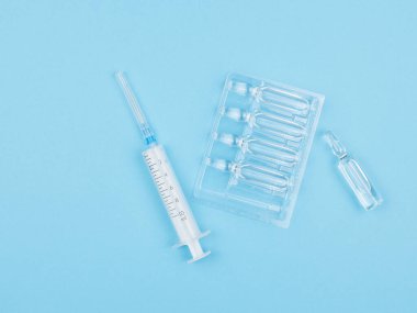 Mavi arka planda bir şırınga ve ampul. Yukarıdan görünüşü.