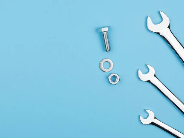 Mavi arka planda manüel anahtarlar, cıvatalar ve fındıklar. Tamirci. Yukarıdan görünüşü.