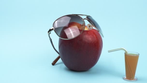 Яблоко в солнечных очках и коктейль с соломинкой . — стоковое видео