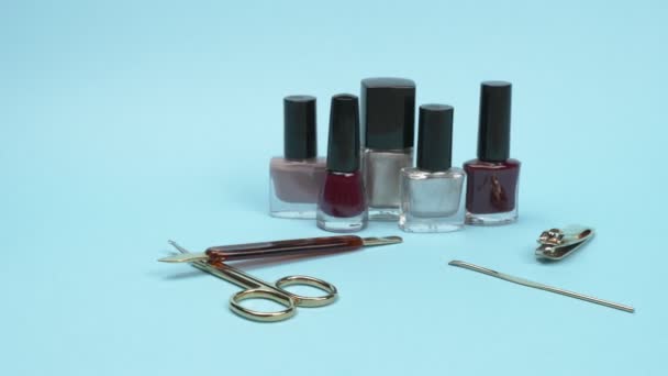 Vernissen voor nagels en accessoires voor manicure op de blauwe achtergrond. — Stockvideo