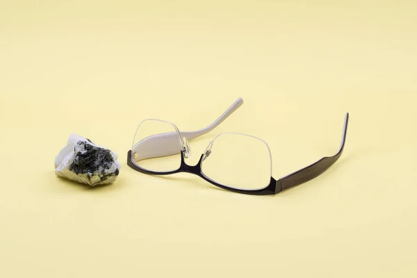 Óculos e pedra da lua em um fundo amarelo . — Fotografia de Stock