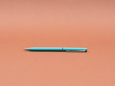 Kahverengi arkaplanda turkuaz kalem yakın plan.