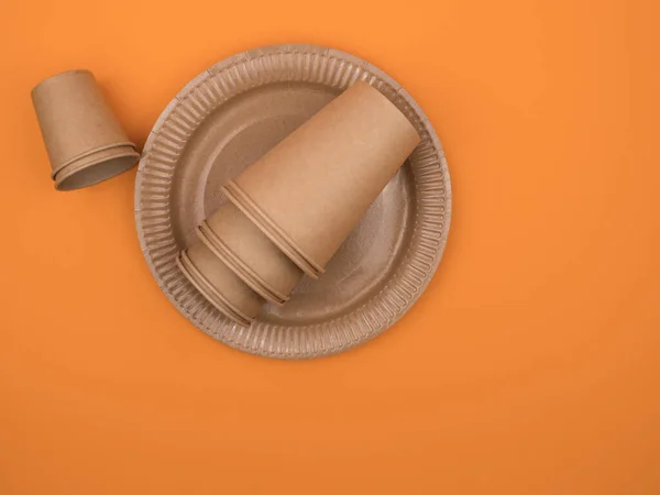 Kartonnen keukengerei en picknick op een oranje achtergrond. — Stockfoto