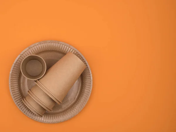 Papieren bekers en borden op een oranje achtergrond. — Stockfoto