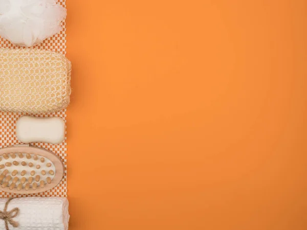 Washandje, zeep en andere badkameraccessoires op een oranje achtergrond. — Stockfoto