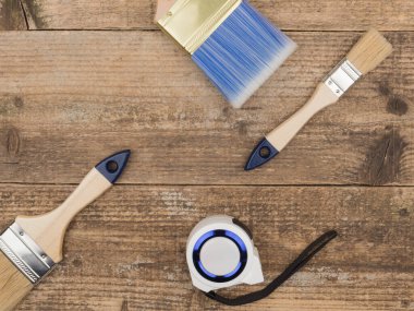 Boya fırçaları ve ahşap arka planda inşaat sayacı.