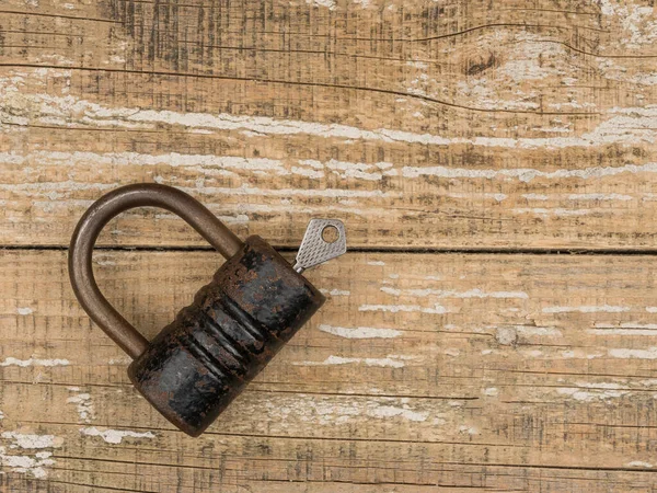 Old padlock with key on a wooden background. — Stock Photo, Image