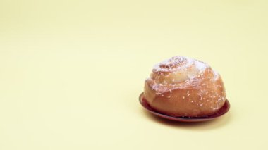Sarı arka planda bir fincan tabağında tatlı çörek.