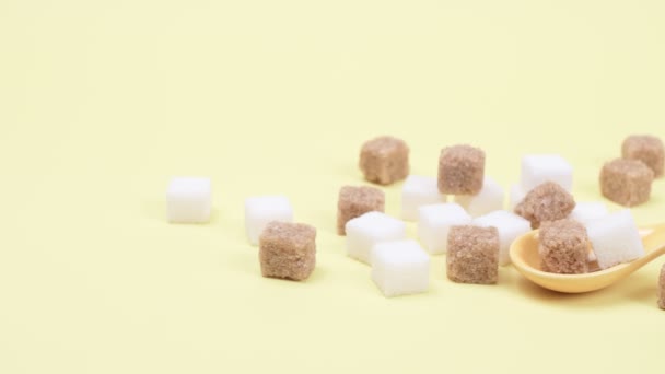 Vitt och brunt socker i bitar på en gul bakgrund. — Stockvideo