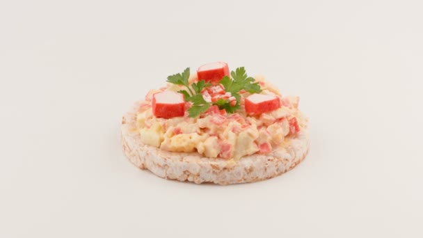Sandwich avec garniture de bâtonnets de crabe sur un pain de riz rond . — Video
