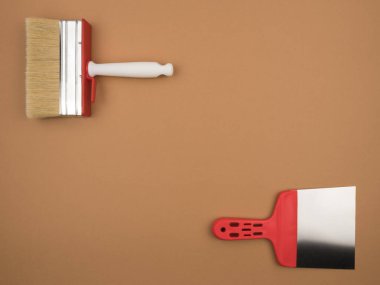 Bej arkaplanda büyük kırmızı fırça ve spatula..