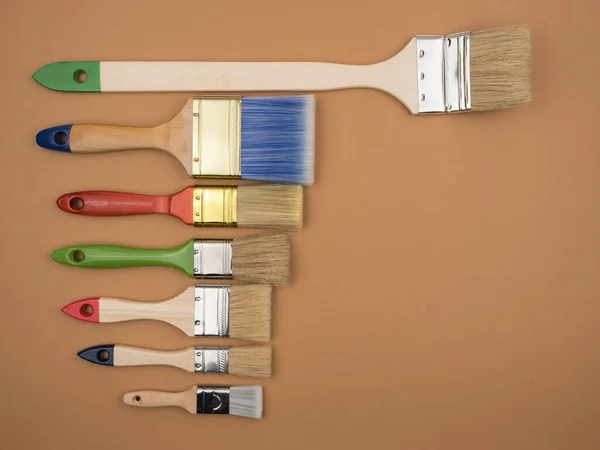 Different brushes for painting on a beige background. — Stock Photo, Image