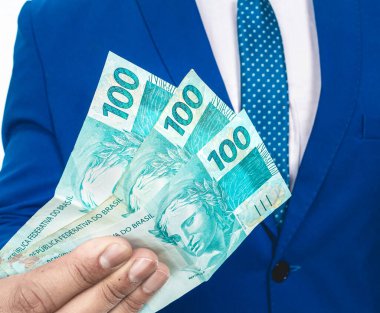 Gerçek para birimi. Dinheiro, Brasil, Money, Reais. Elinde 100 Brezilyalı banknot tutan adam.