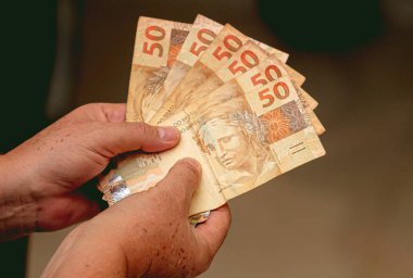 Gerçek Brezilya parası. Para, Dinheiro, Brezilya, Reais. Bir grup gerçek banknot tutan bir kadın..