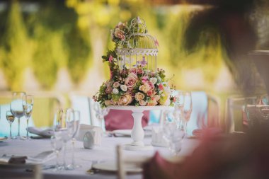 Vazolarında pembe çiçekler olan düğün süsü. Misafirler için masa, çatal bıçak, çiçek ve çanak çömlek ile servis edilir ve masa örtüsüyle kaplanır. Zarif tablo manzarası.