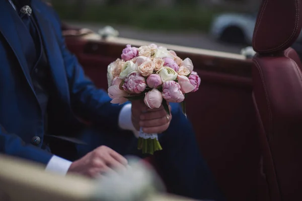 wedding bouquet of flowers in the hands of the groom. Beautiful wedding bouquet of flowers.