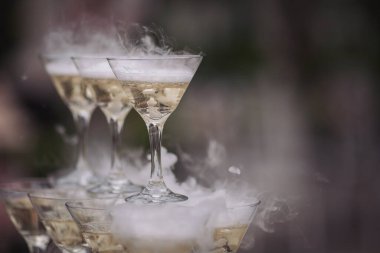 Parti ve tatil kutlaması konsepti. Restorandaki masada birçok bardak şampanya var. Şampanyayı bardakla şişeleme işlemi. Garson bardağa şampanya dolduruyor.