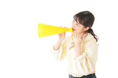 Beyaz arka planda izole edilmiş sarı megafonlu Asyalı genç kadının portresi.