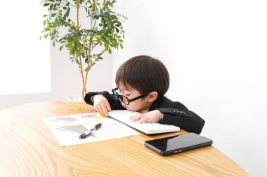 Küçük çocuk masa başında oturup grafikleri analiz ediyor. 