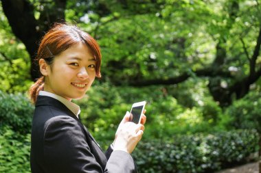Parkta cep telefonu kullanan Asyalı iş kadınının portresi