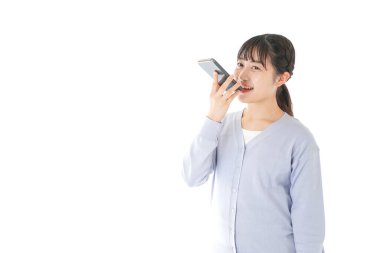 Asyalı bir kadın cep telefonuyla ses kaydı yapıyor.