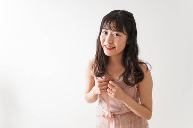 Beyaz arka planda izole edilmiş pembe elbiseli Asyalı genç kadın portresi.