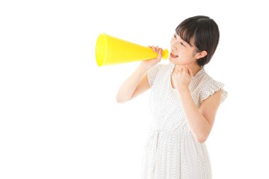 Beyaz arka planda izole edilmiş sarı megafonlu Asyalı genç kadının portresi.