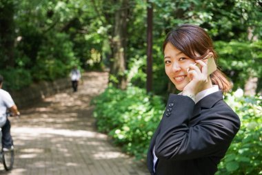 Parkta cep telefonuyla konuşan Asyalı iş kadınının portresi