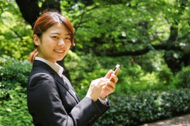 Parkta cep telefonu kullanan Asyalı iş kadınının portresi
