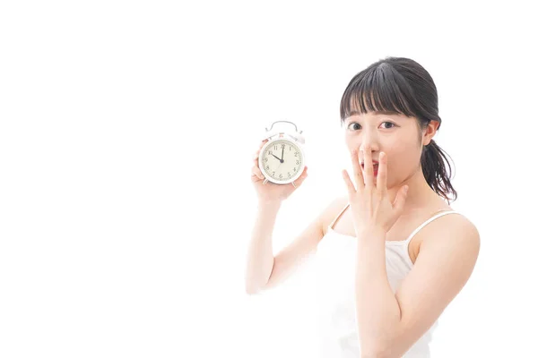 白い背景に目覚まし時計を持つ若いアジアの女性は — ストック写真