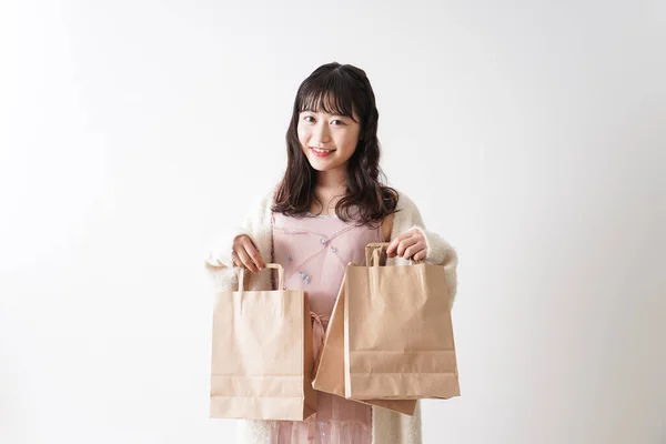 白い背景に孤立した紙袋を持ったアジア系の若い女性の肖像画 — ストック写真