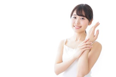 Beyaz arka planda izole edilmiş krem süren Asyalı genç kadın portresi