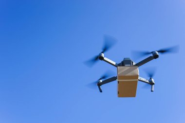 Mavi gökyüzüne karşı uçan drone taşıyor, İHA teslimatı