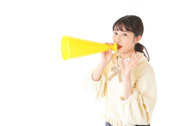 Beyaz arka planda izole edilmiş sarı megafonlu Asyalı genç kadının portresi.