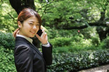 Parkta cep telefonuyla konuşan Asyalı iş kadınının portresi