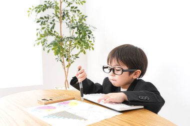 Küçük çocuk masa başında oturup grafikleri analiz ediyor. 