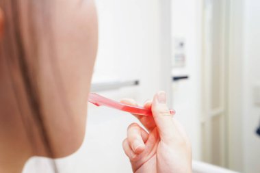 Banyoda dişlerini fırçalayan kadının elini kapat.