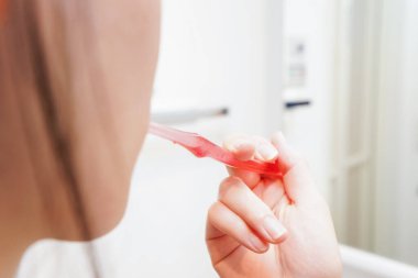 Banyoda dişlerini fırçalayan kadının elini kapat.