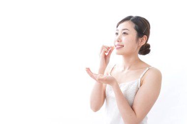 Genç Asyalı kadın beyaz arka planda izole edilmiş haplar ve kapsüller alıyor.