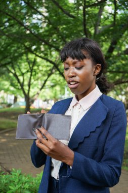 Genç Afrikalı iş kadını parkta cüzdanını tutuyor.