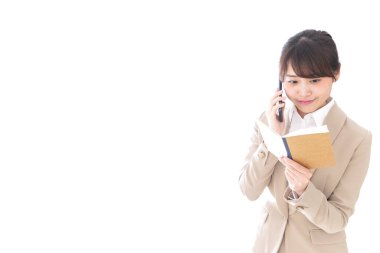 Not defterli Asyalı iş kadını beyaz arka planda cep telefonuyla konuşuyor.