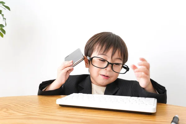 little boy studying using desktop pc  and mobile phone