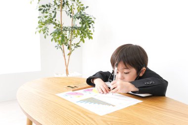 Küçük çocuk masa başında oturup grafikleri analiz ediyor. 