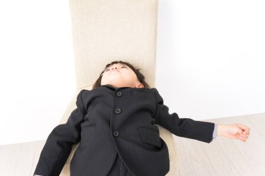 Stüdyoda beyaz arka planda poz veren takım elbiseli ve gözlüklü küçük çocuk.