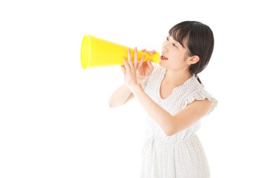 Beyaz arka planda izole edilmiş sarı megafonlu Asyalı genç kadının portresi.