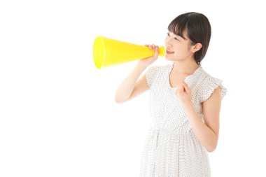 Beyaz arka planda izole edilmiş sarı megafonlu Asyalı genç kadının portresi.
